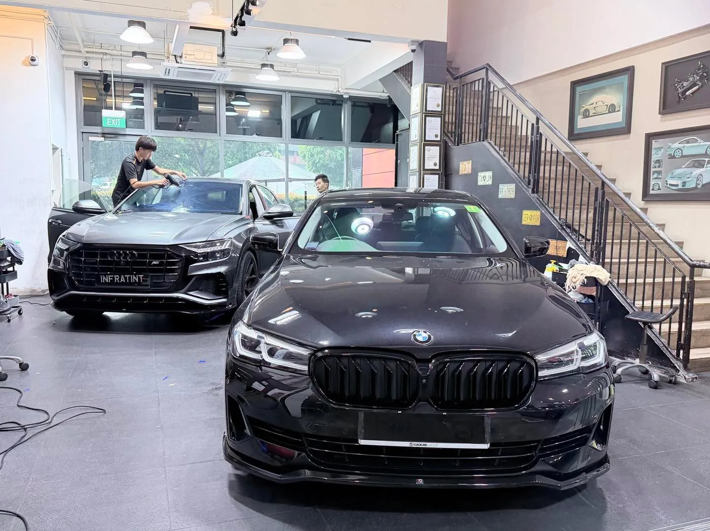 A black Audi Q8 SUV and a dark Tesla parked indoors.
