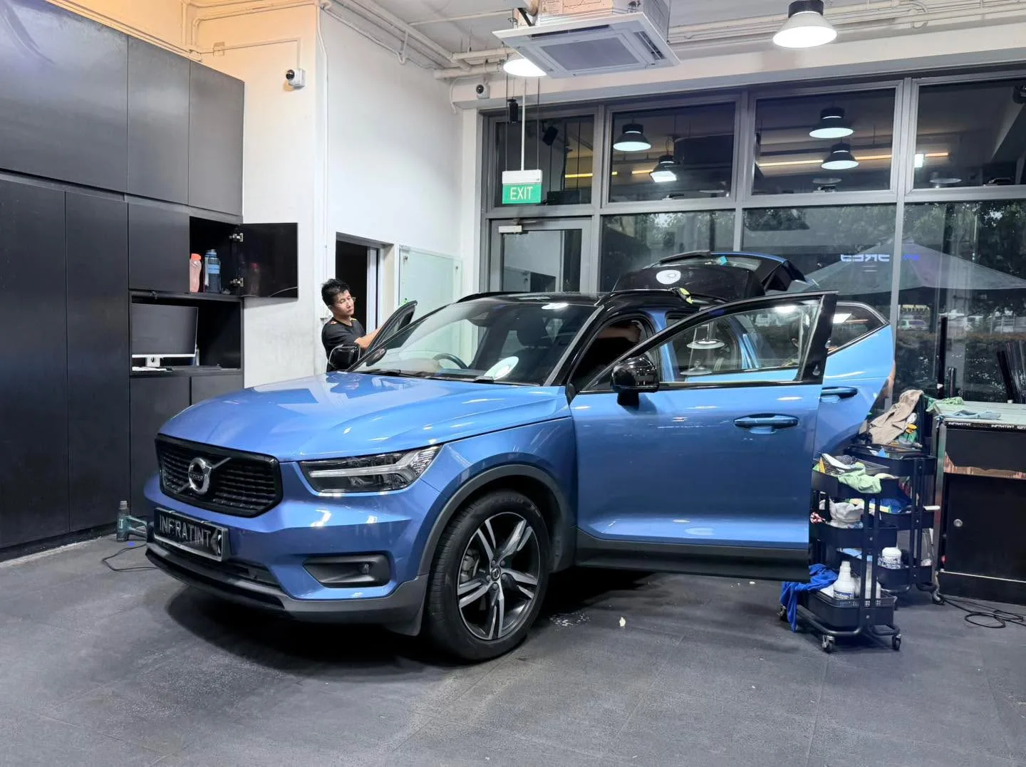 A bright blue Volvo XC40 with the door open, being tinted indoors.