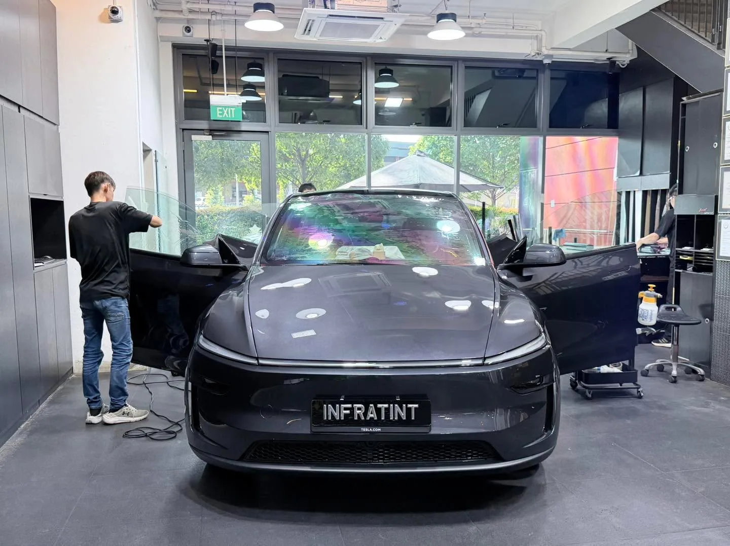 A black Tesla Model Y being worked on indoors, door open.