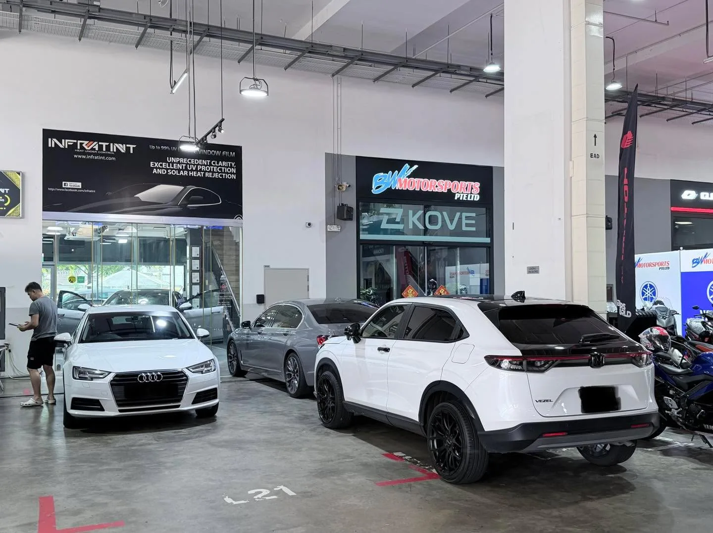 A white Audi A4, a silver Audi sedan, and a white Honda Vezel parked in the workshop.