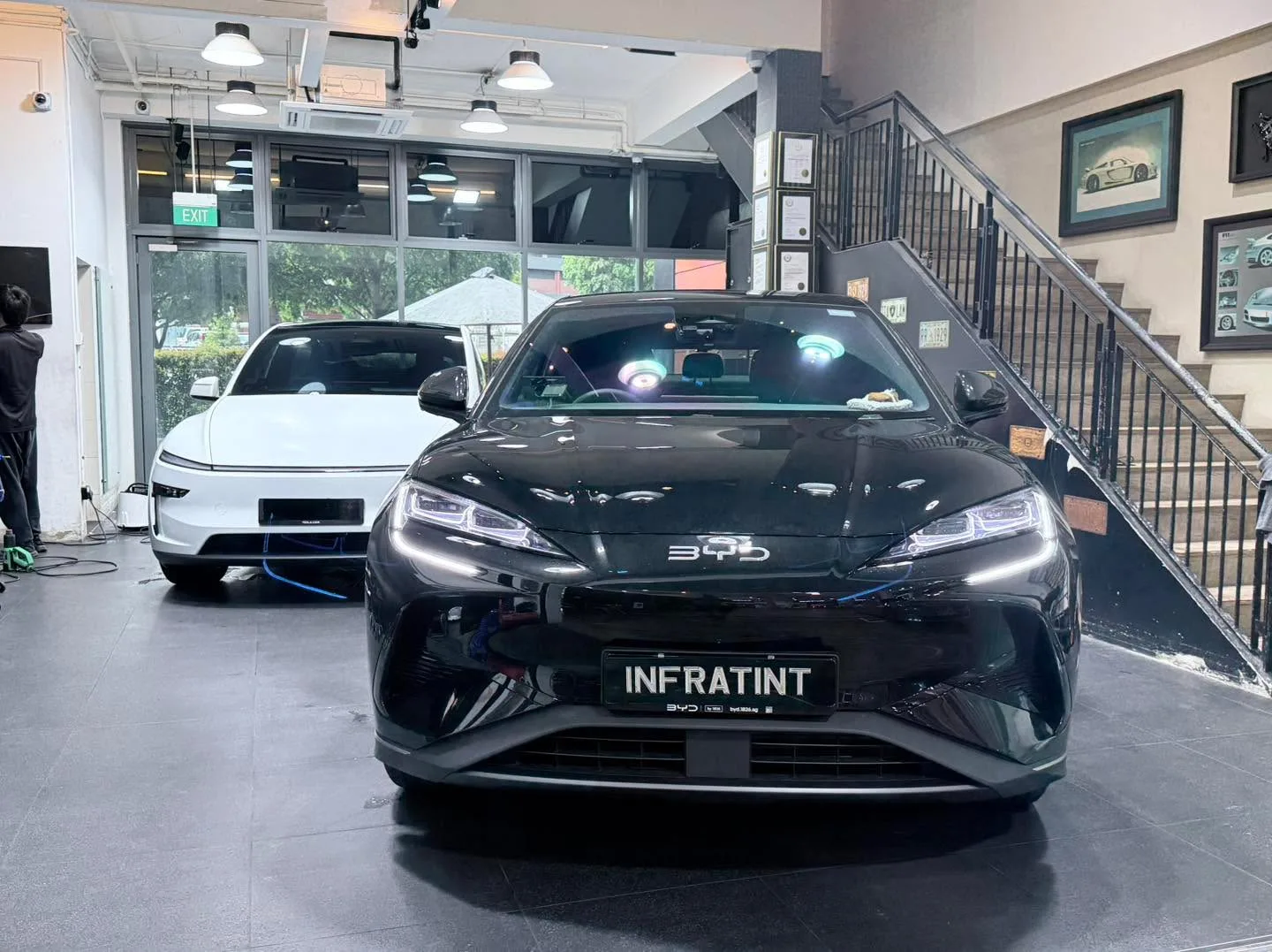 A black Maserati GranTurismo and a white vehicle visible in the workshop.