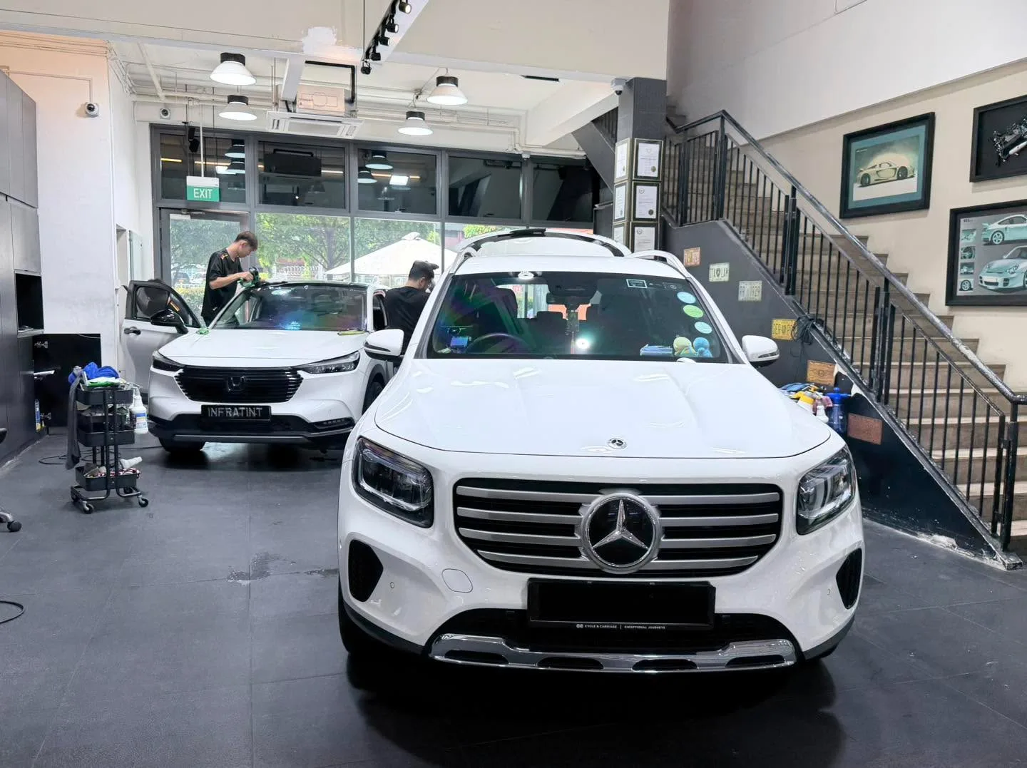 A white Mercedes-Benz GLB parked in the workshop with other vehicles.