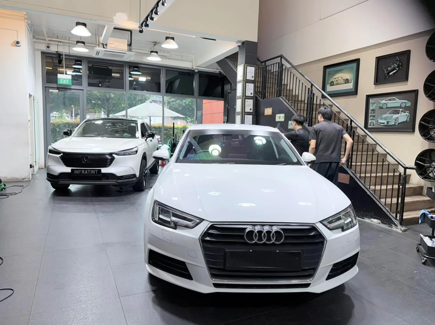 A white Audi A4 and a white Honda Vezel parked in the workshop.