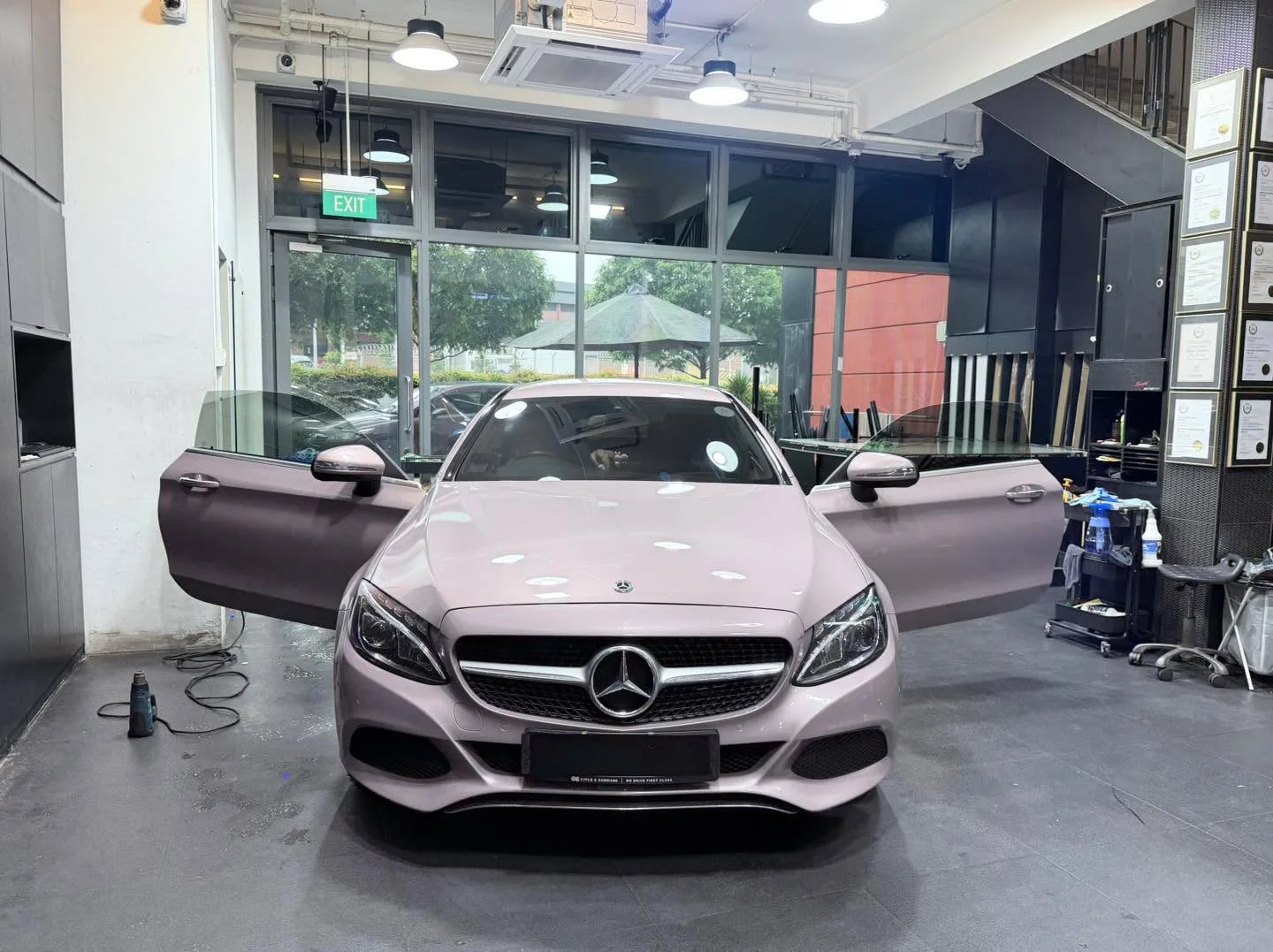 A light pink Mercedes-Benz C-Class saloon with its doors open, parked indoors.