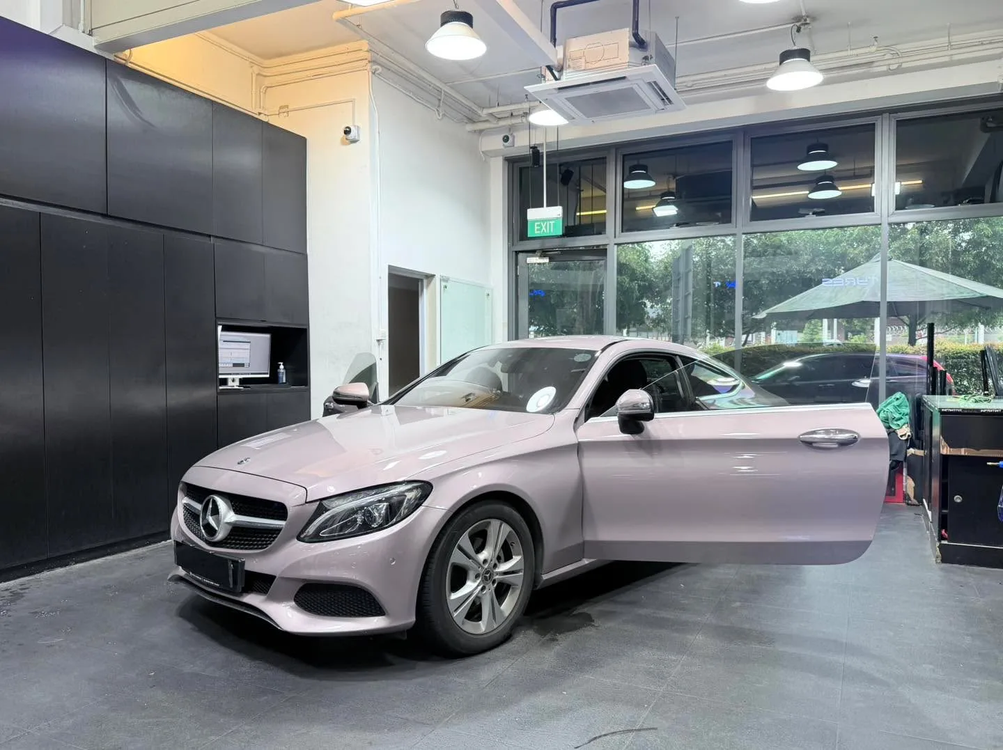 A light pink Mercedes-Benz C-Class saloon with both doors open, parked indoors.
