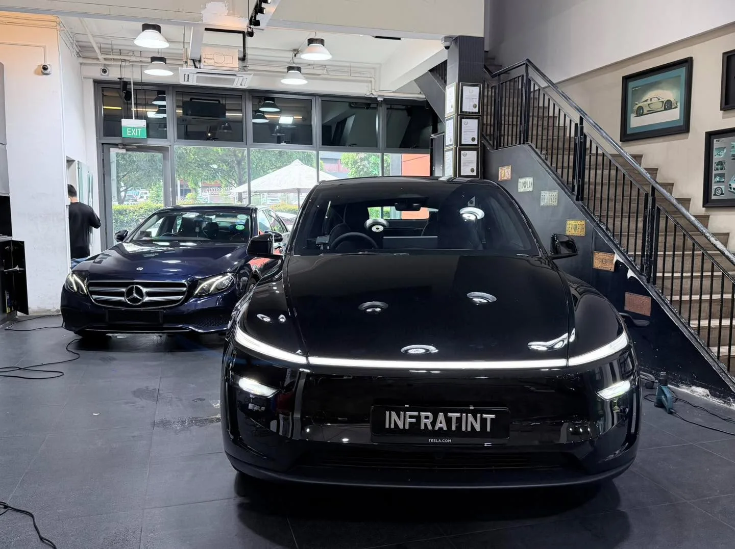 A black electric sedan with Infratint branding on the number plate, parked indoors.