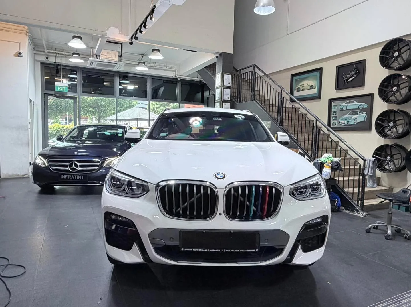 A white BMW X SUV with distinctive kidney grille, parked indoors facing forward.