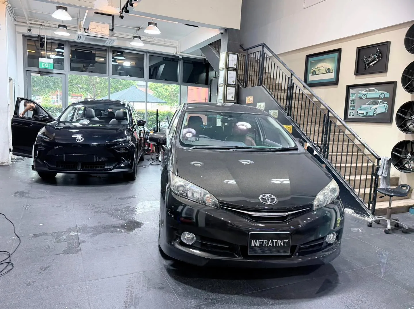 A white BMW X SUV and a black saloon parked indoors side by side.
