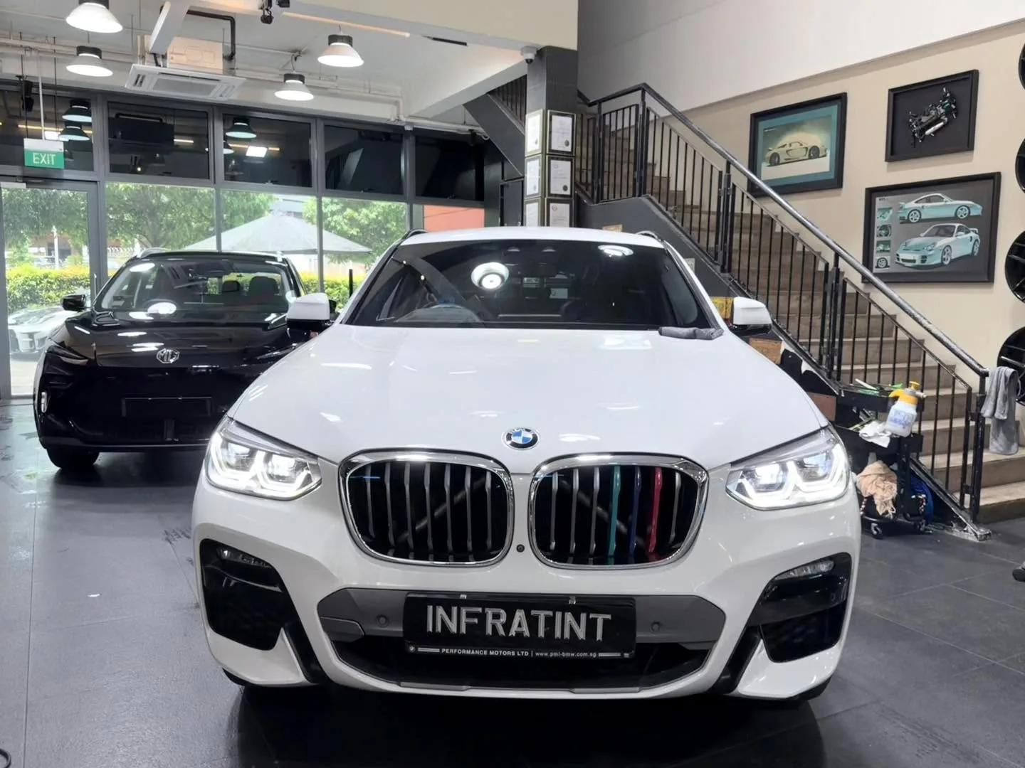 A white Toyota hatchback and a white BMW X SUV parked indoors.
