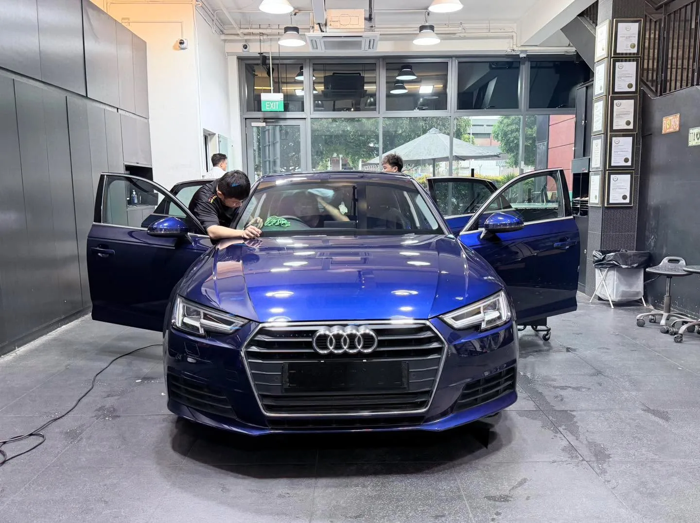 A dark blue Audi sedan with doors open, being worked on indoors.