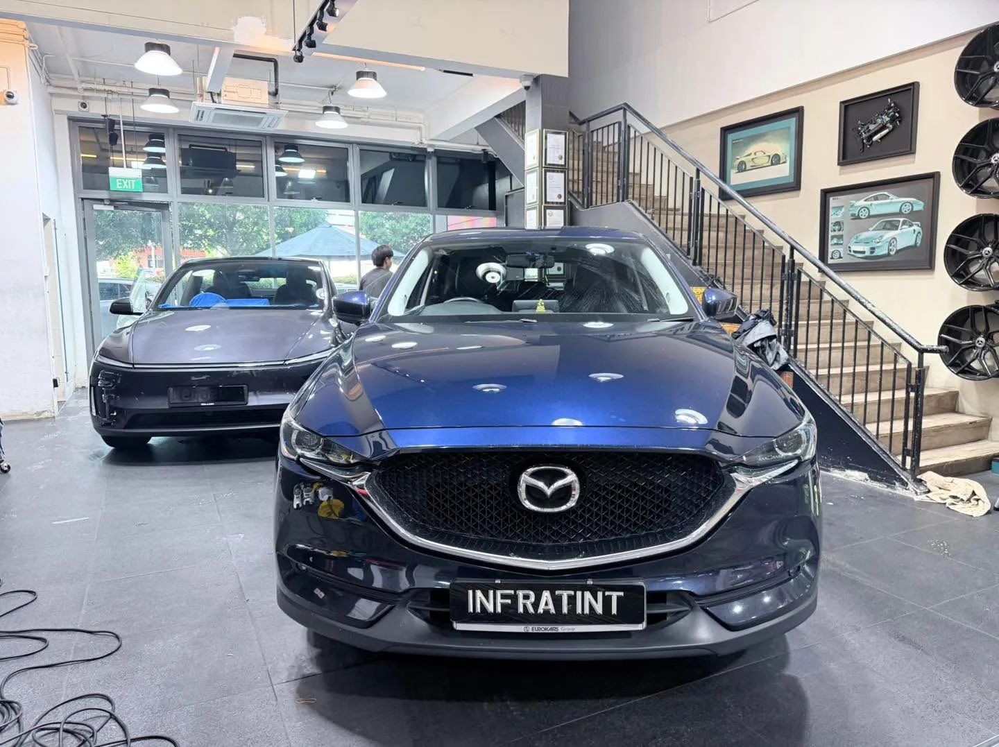 A blue Mazda SUV with doors open at an indoor facility.