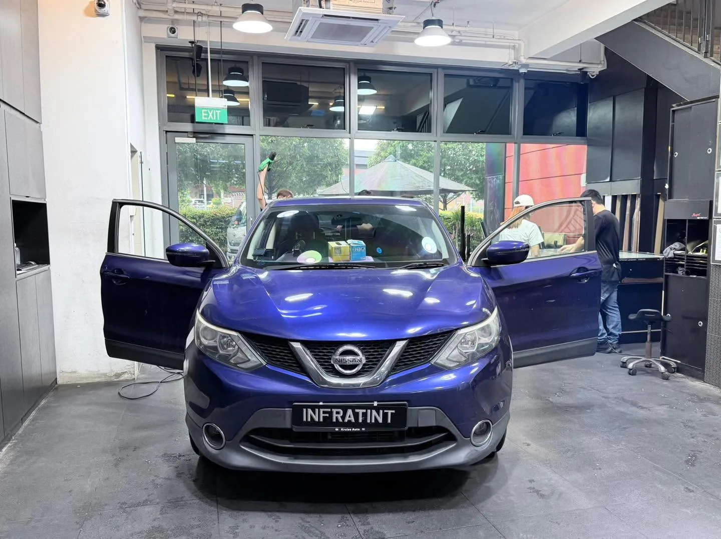 A blue Nissan SUV with doors open in the workshop.