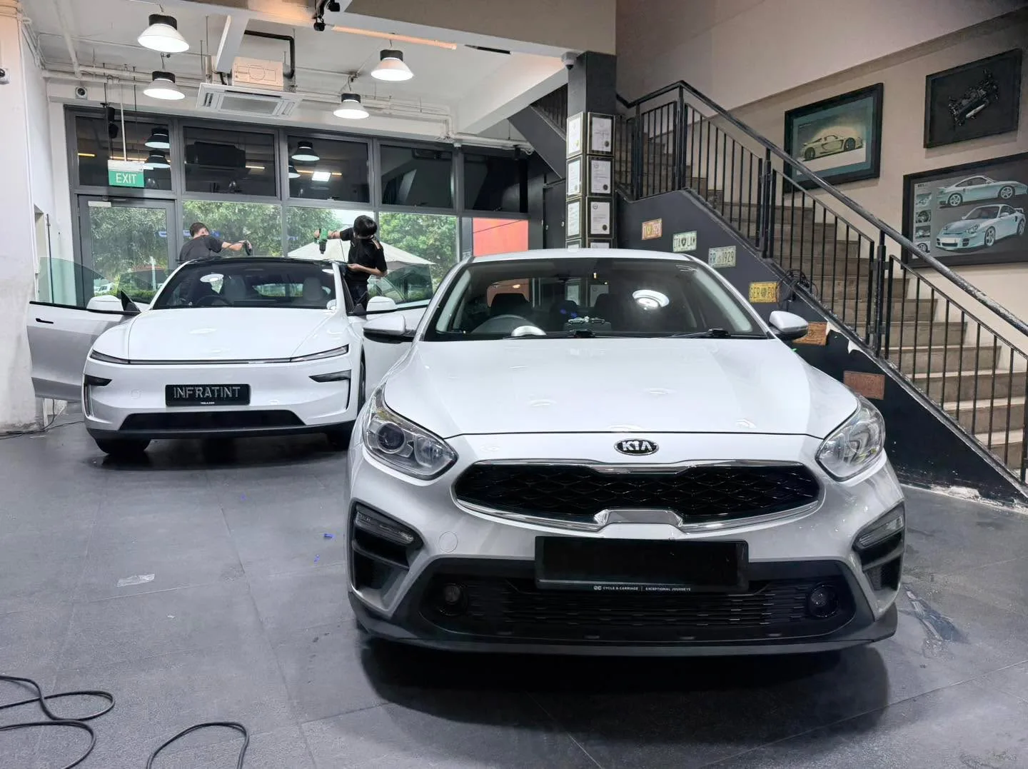 A white Kia Cerato and white Tesla sedan parked in the workshop.