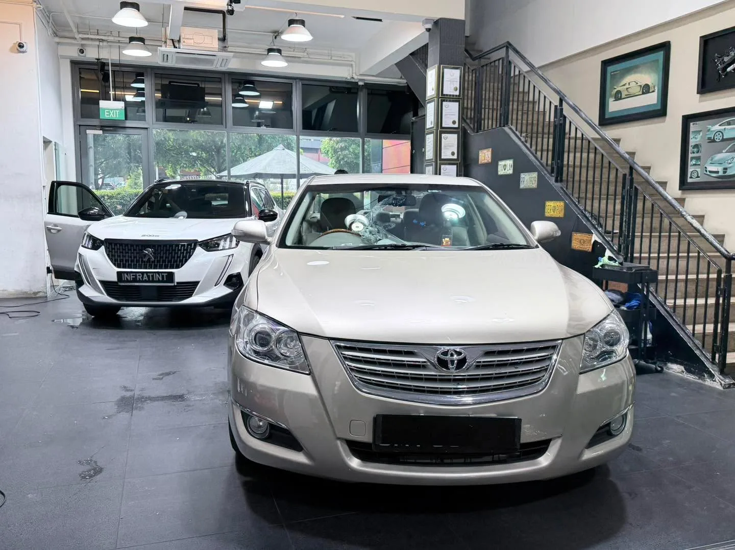 A white Peugeot and a beige Toyota sedan in the workshop.
