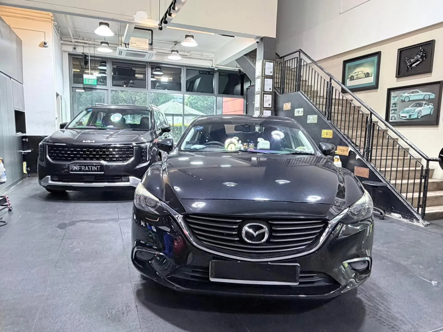 A black Mercedes-Benz sedan and a black Kia SUV in the workshop.