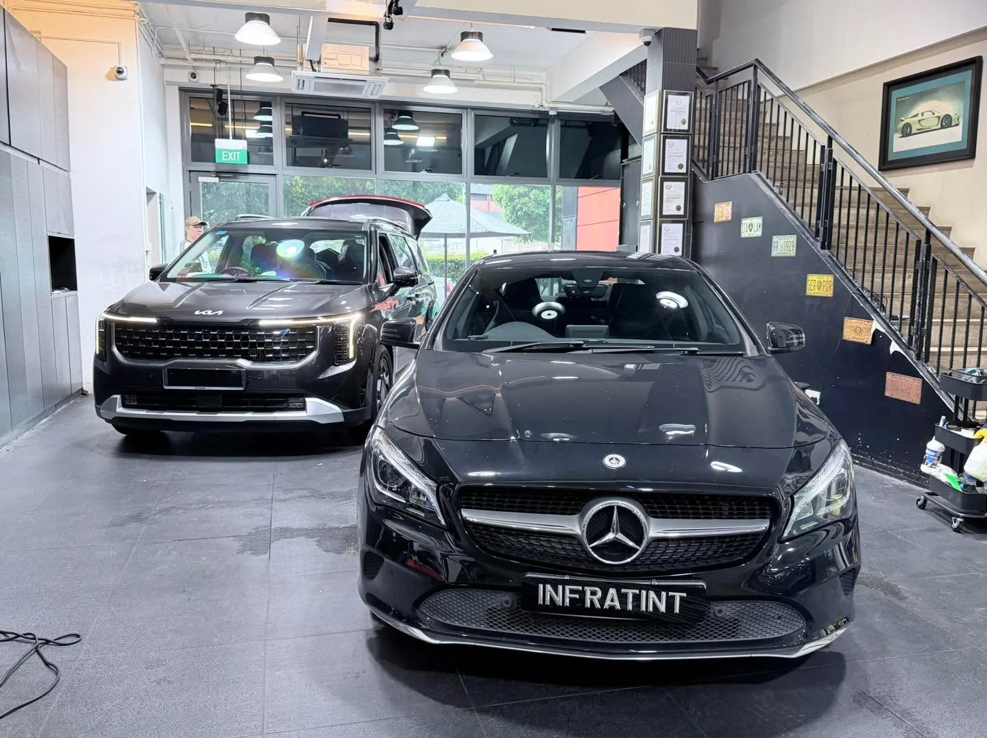 A black Kia SUV and a black Mercedes-Benz sedan in the workshop.