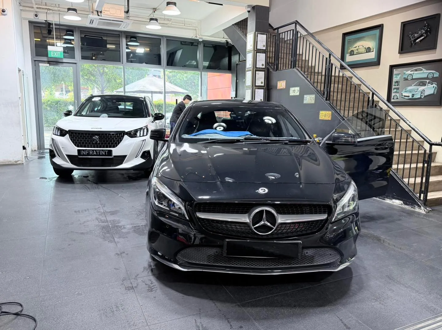 A white Peugeot and a black Mercedes-Benz sedan in the workshop.