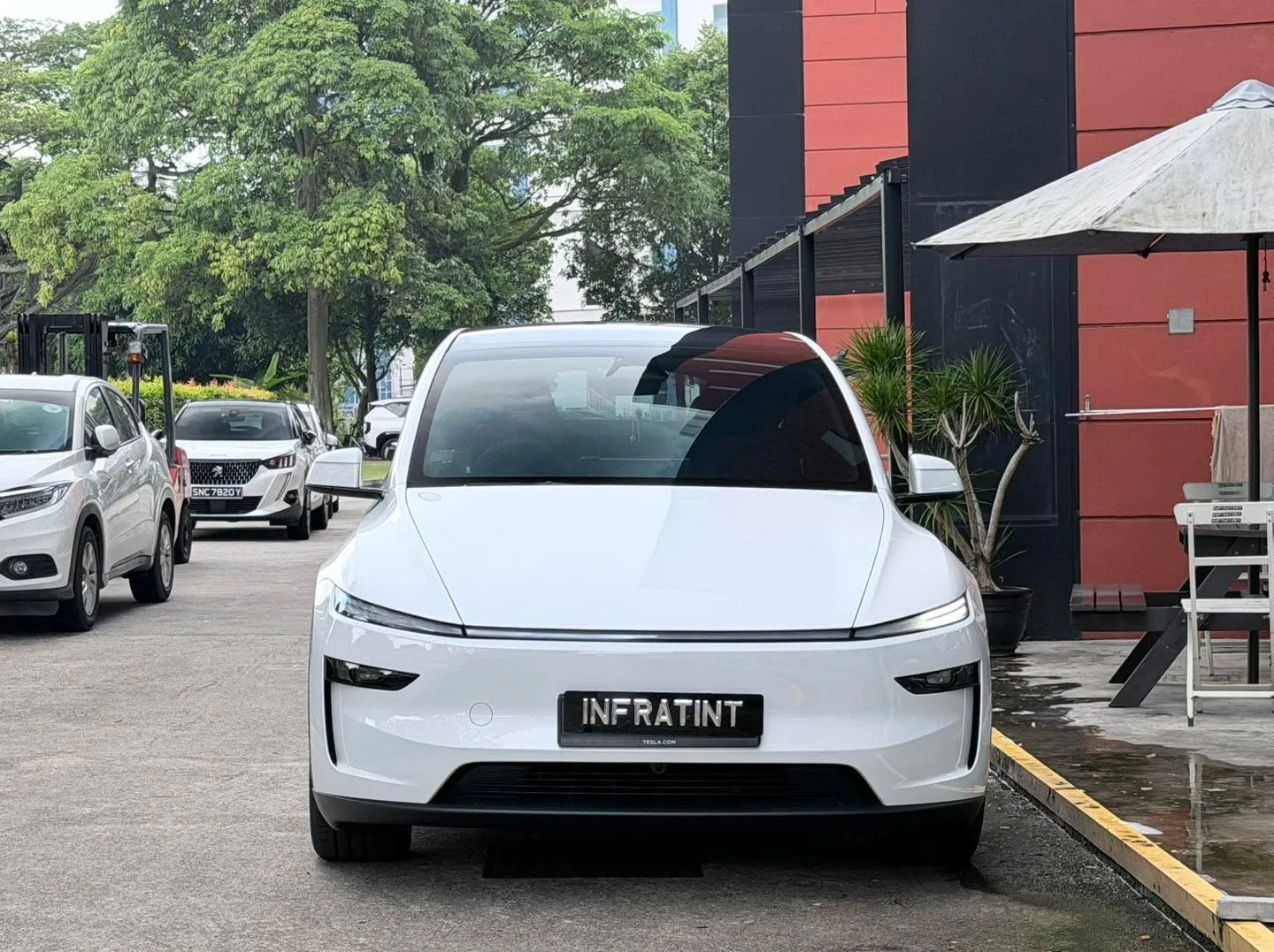 A silver Tesla Model Y is parked outdoors, viewed from the front.