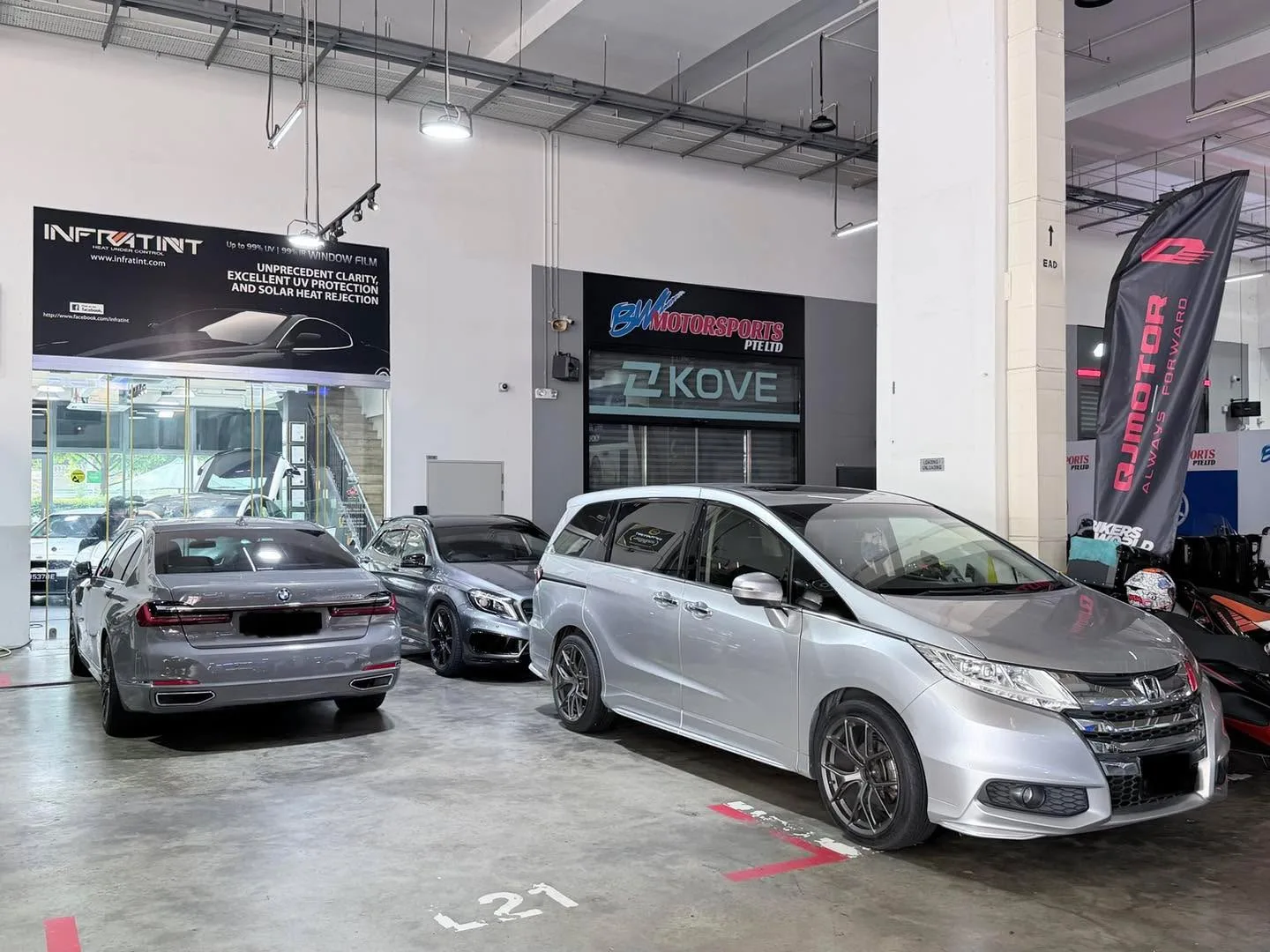 Three silver and black cars parked in an Infratint workshop with signage visible.