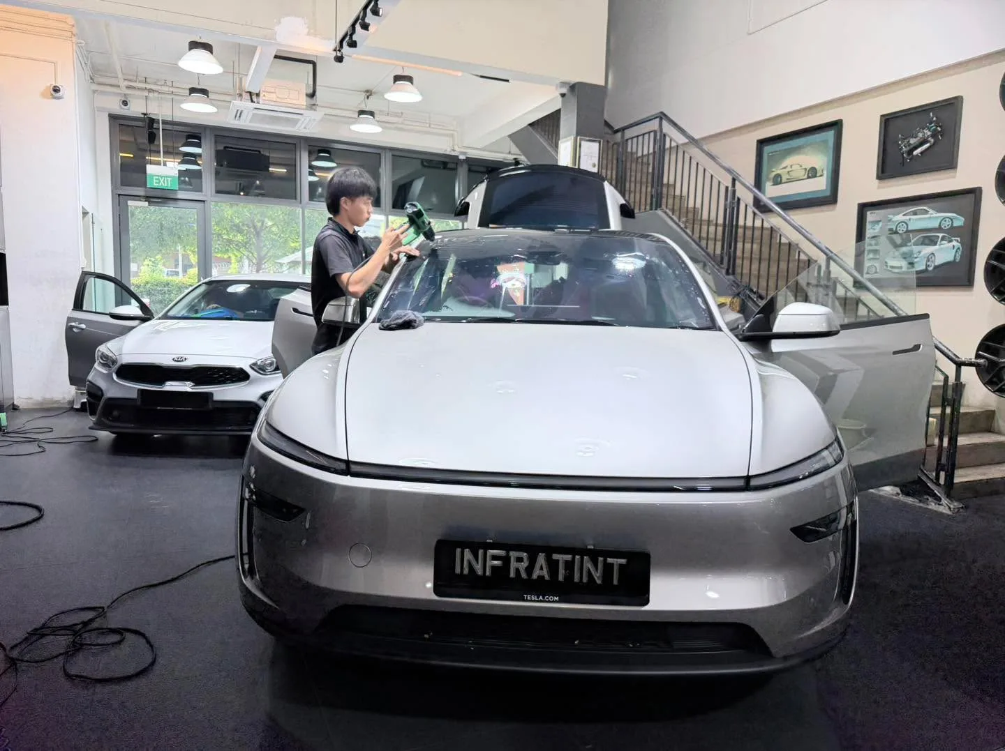 A silver electric sedan with the Infratint nameplate being prepared for window tinting.