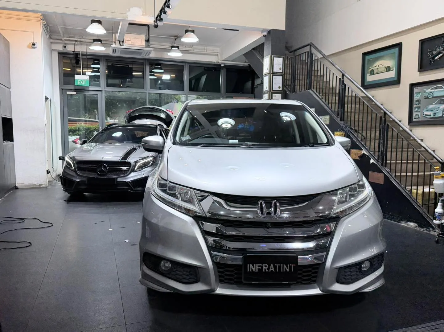 A silver hatchback with Honda badge viewed from the front at the workshop.