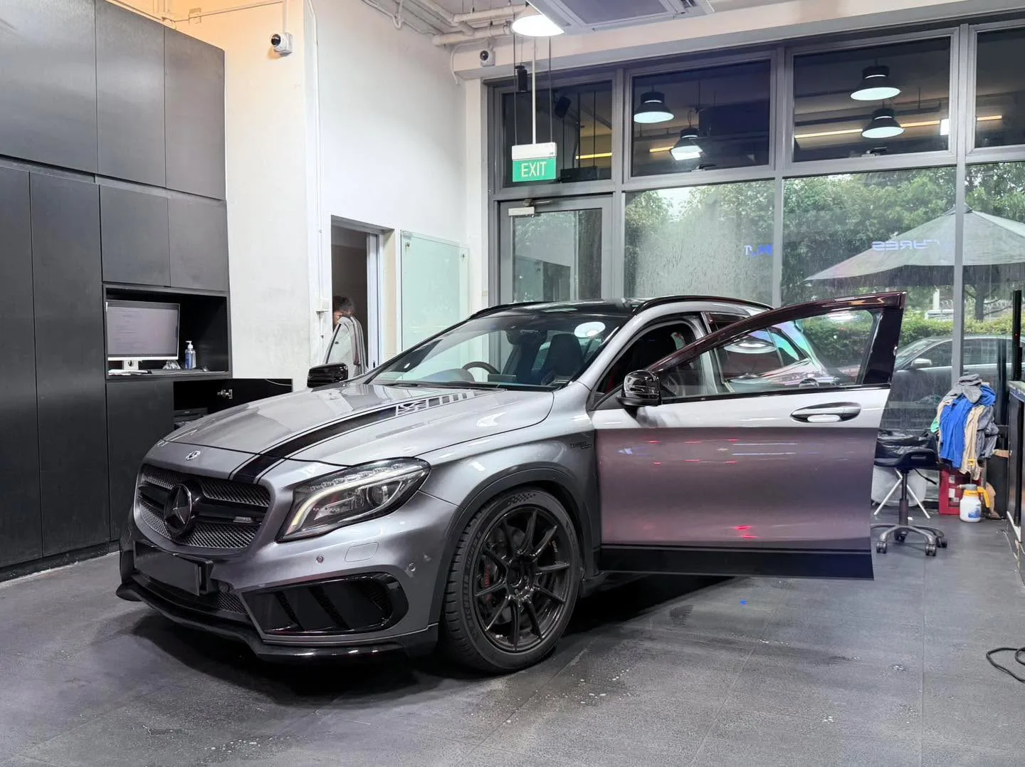 A silver saloon with doors open, showing the Mercedes-Benz logo and striped roof treatment.