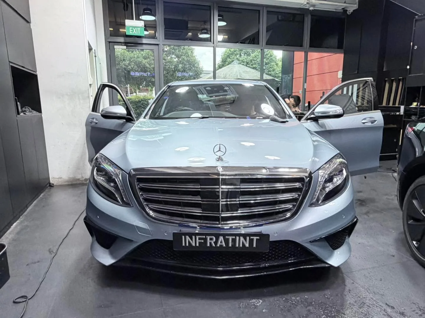 A silver Mercedes-Benz saloon with doors open in the workshop interior.