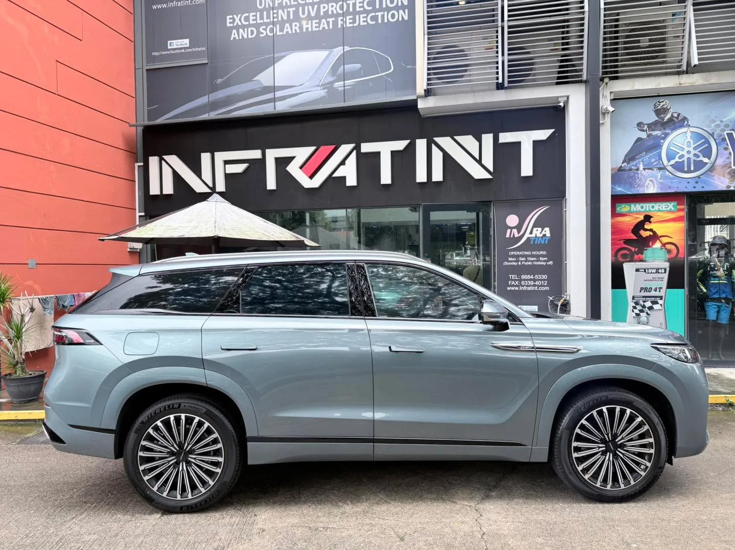 The grey Jaecoo J8 SUV parked in profile beside the Infratint storefront.