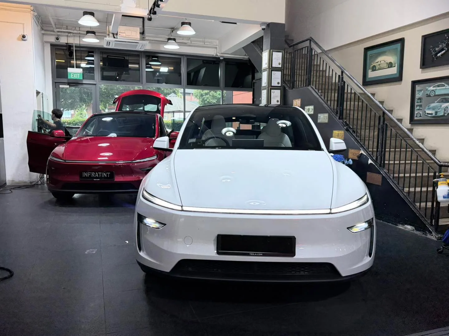 A white Tesla Model Y sedan parked in the centre of the workshop.