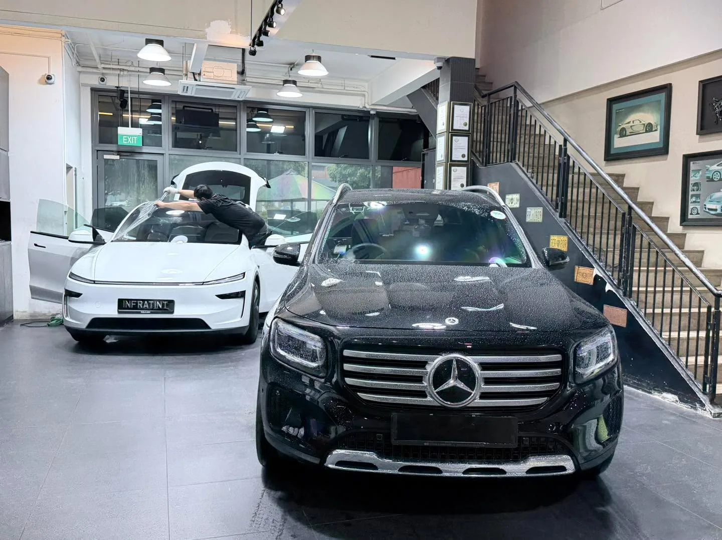 A white Tesla sedan and a black Mercedes-Benz sedan parked indoors.