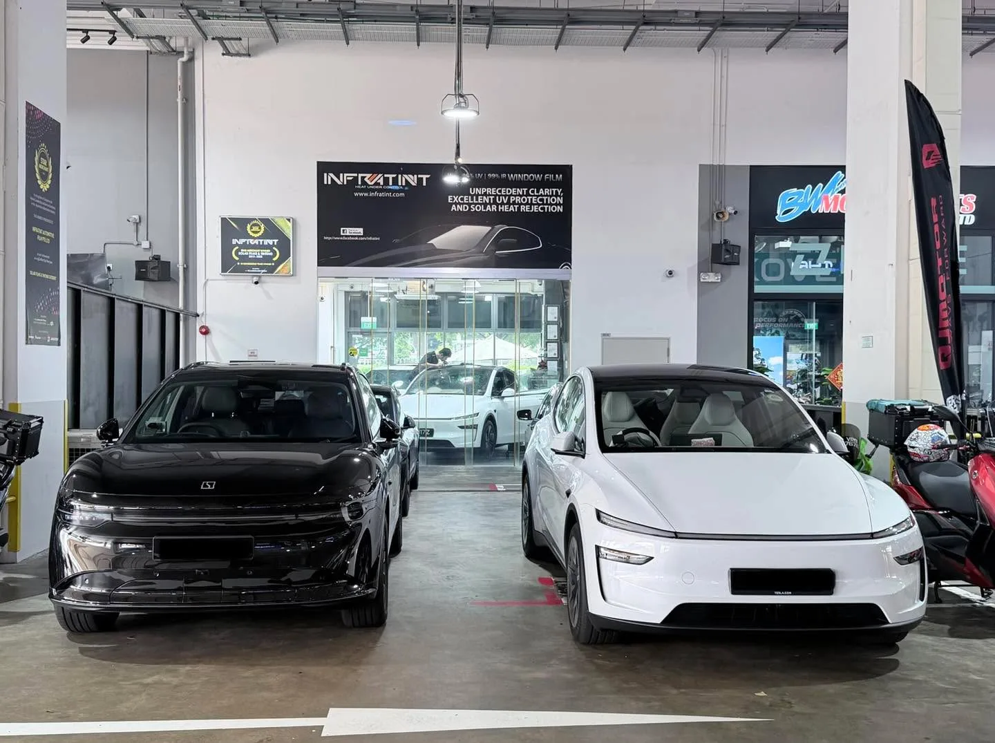 A white Tesla sedan and a black sedan parked indoors at Infratint.