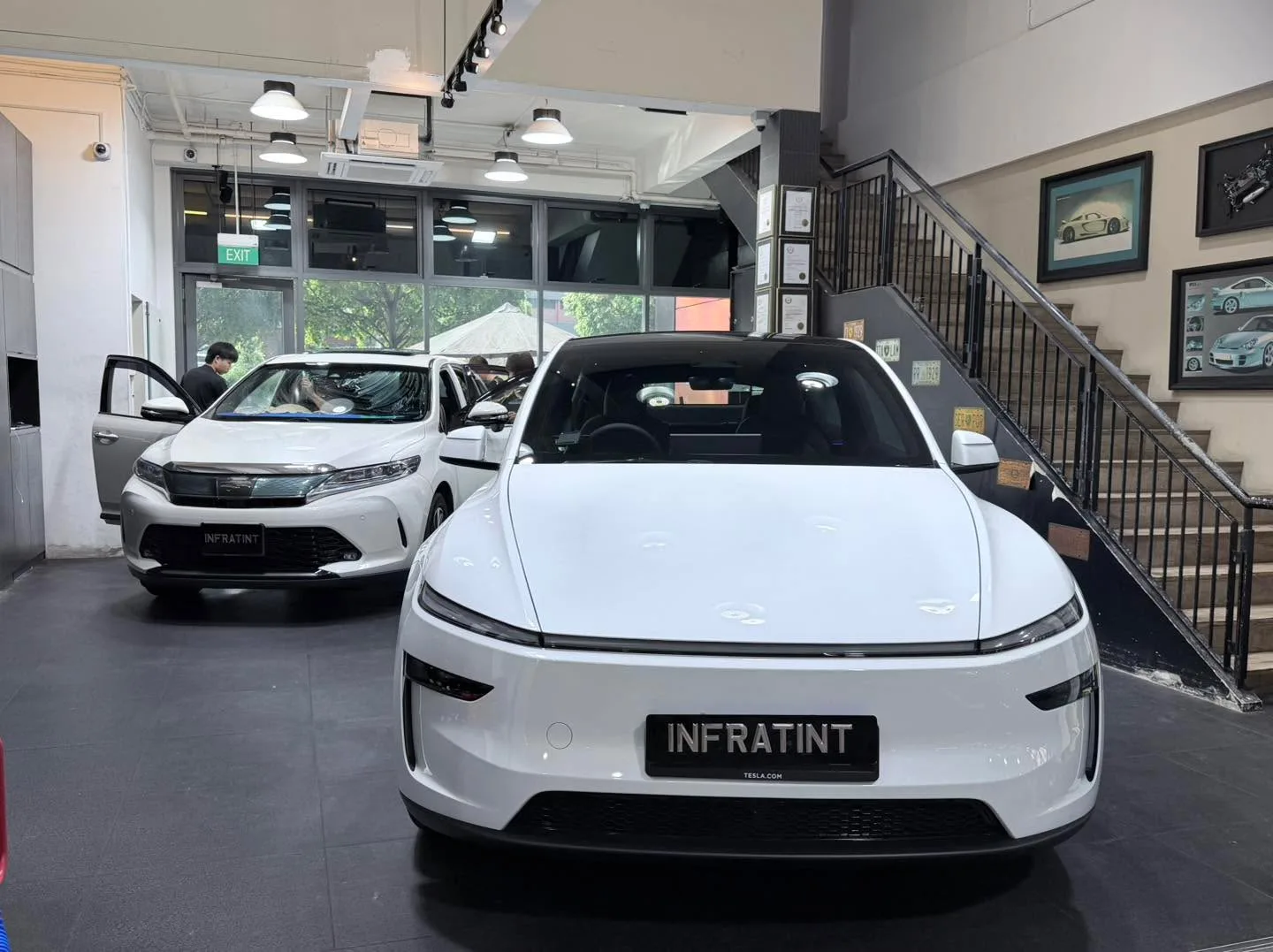 A white Tesla sedan with the Infratint licence plate facing the camera.