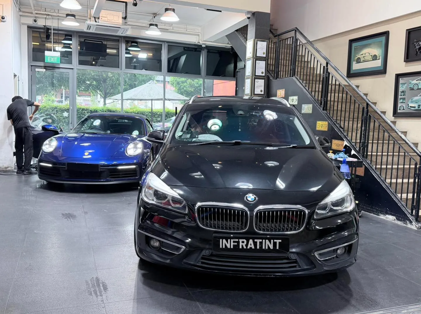 A blue Porsche 911 convertible and a black BMW sedan facing the camera.