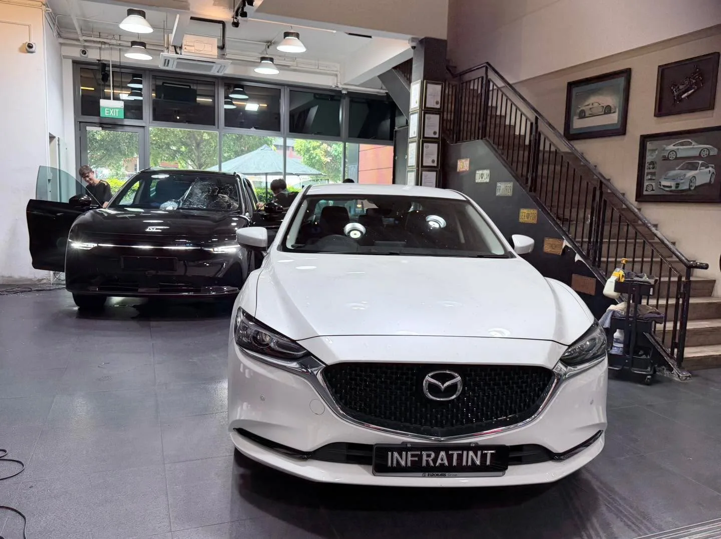 A black BMW sedan with doors open being worked on indoors.