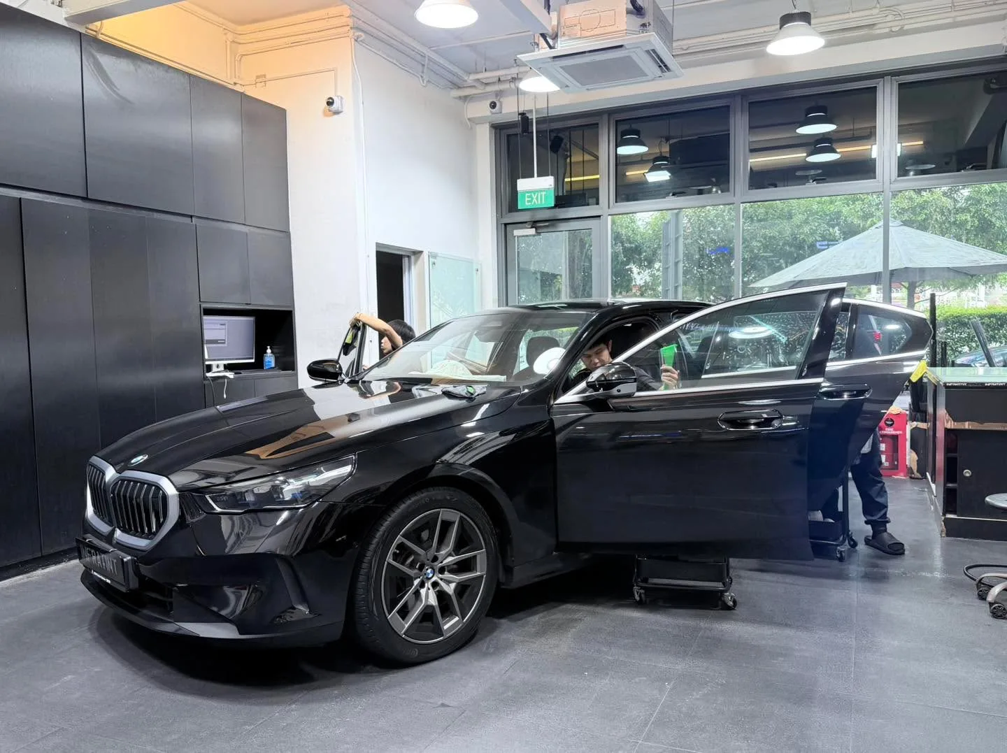 A black BMW sedan with open doors in a bright workshop space.