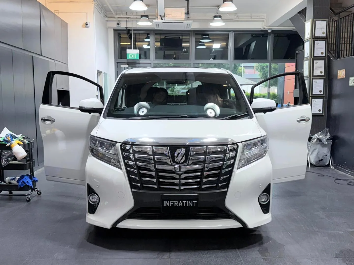A white Toyota Alphard with open doors in the workshop.