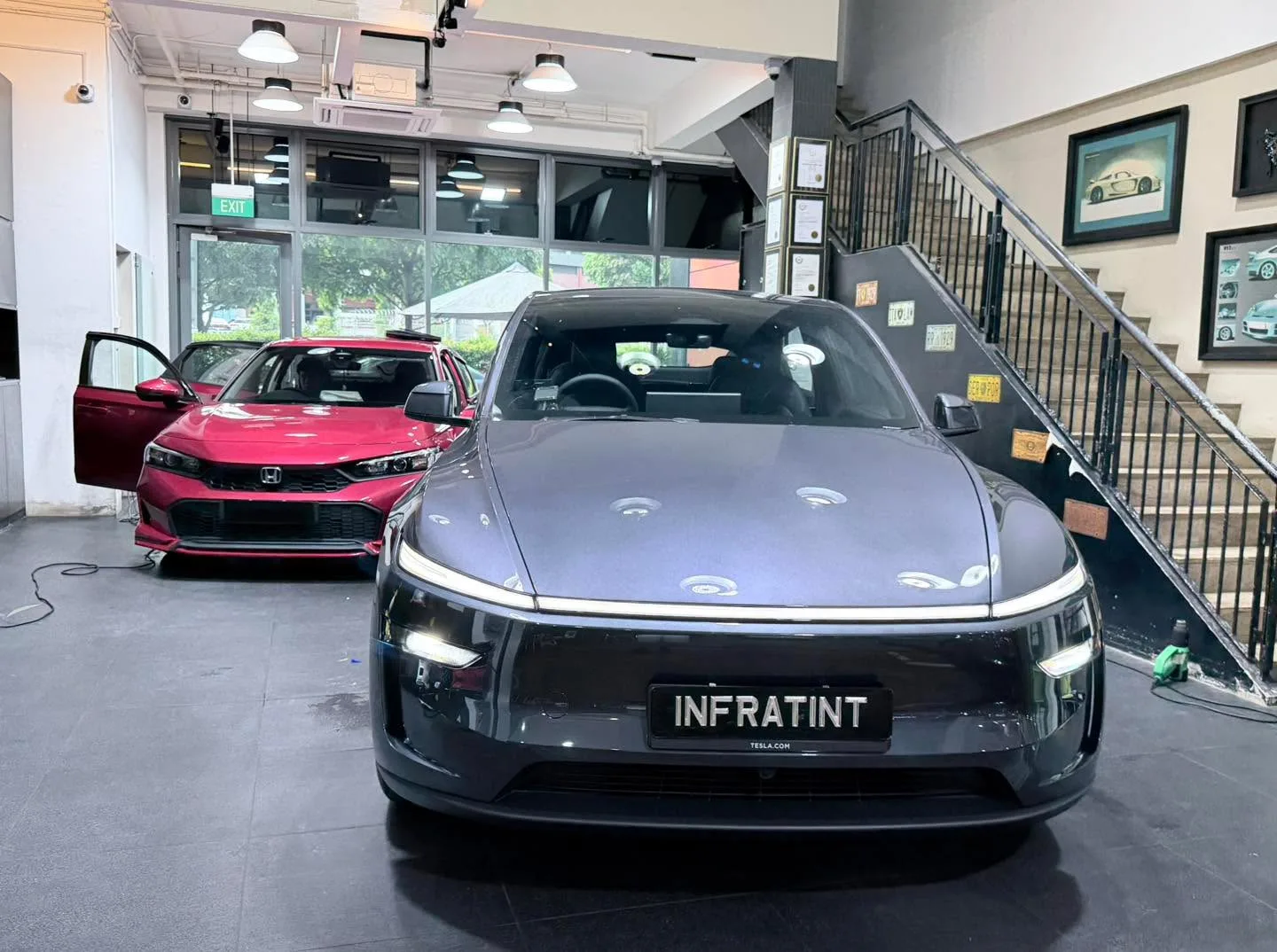A dark grey Tesla sedan with its doors open, parked indoors at Infratint.