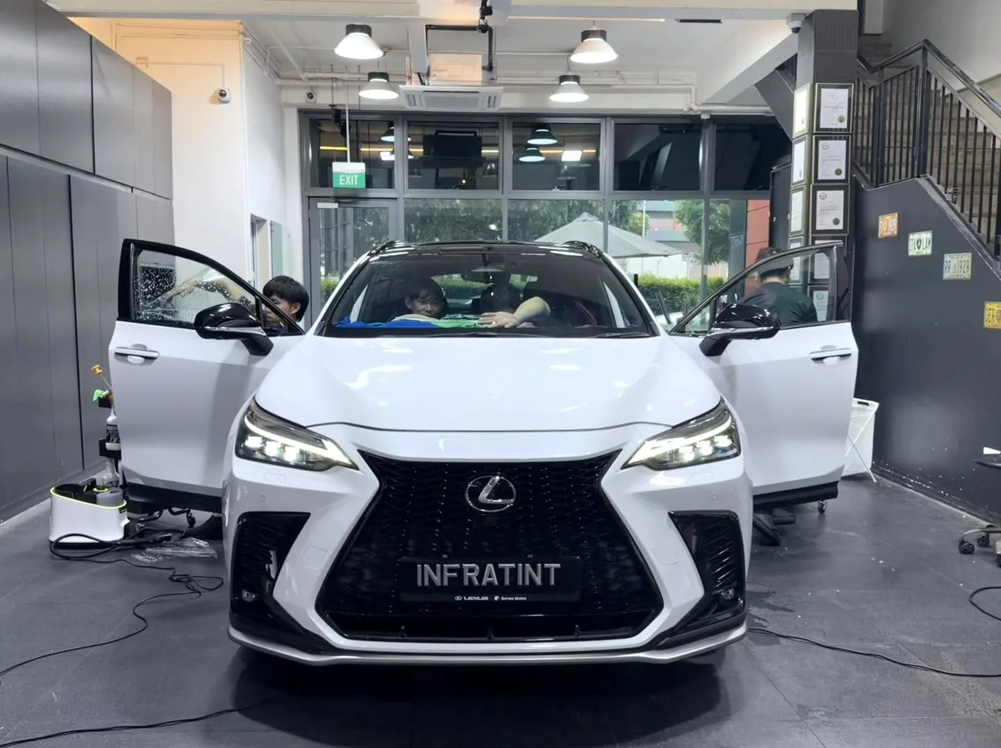 A white Lexus NX350 compact SUV with doors open, parked indoors at Infratint.