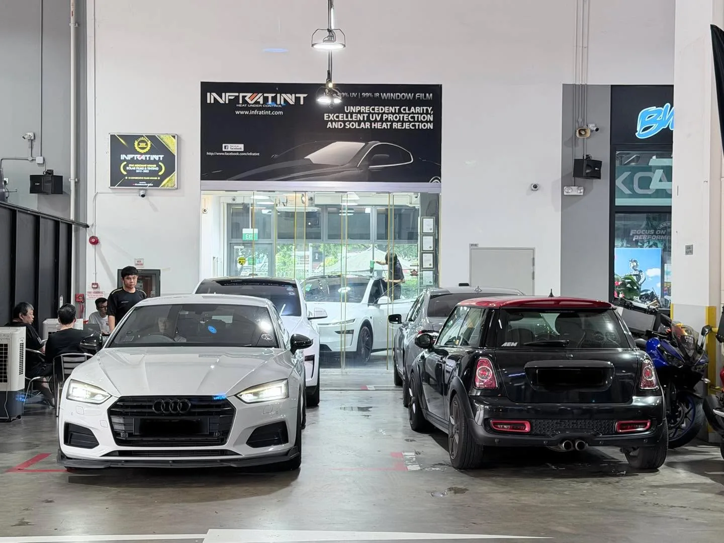 A white Audi A5 and black Mini Cooper S parked in the Infratint workshop floor.