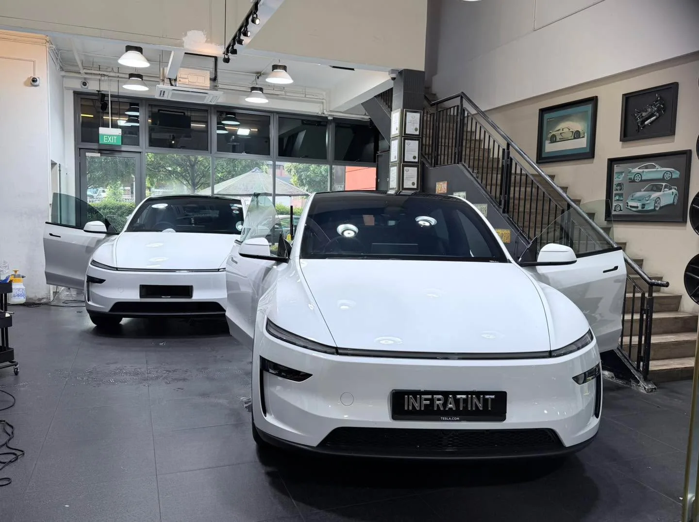 A white Tesla sedan with distinctive front design parked indoors.