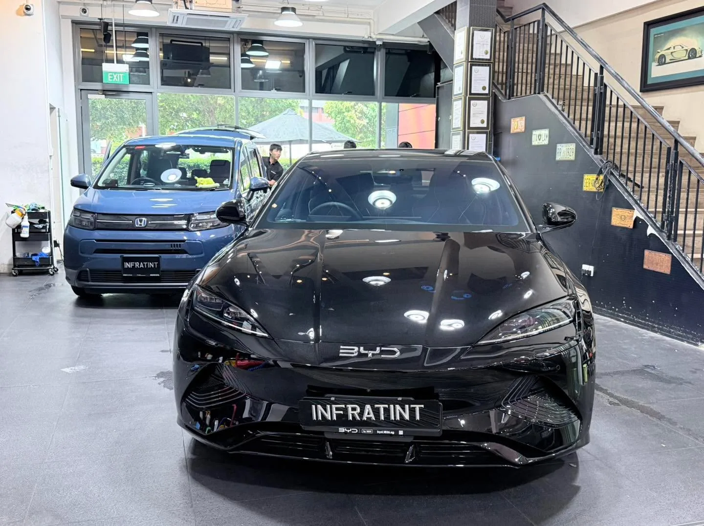 A blue Honda and black BYD sedan in the workshop space.