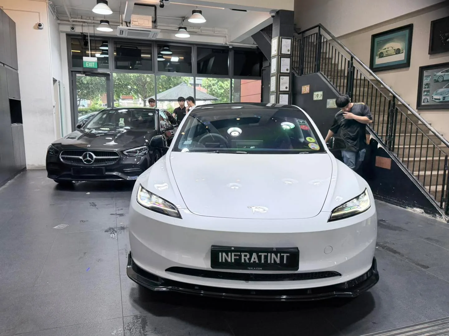 A white Tesla Model Y sedan and black Mercedes-Benz sedan inside the facility.