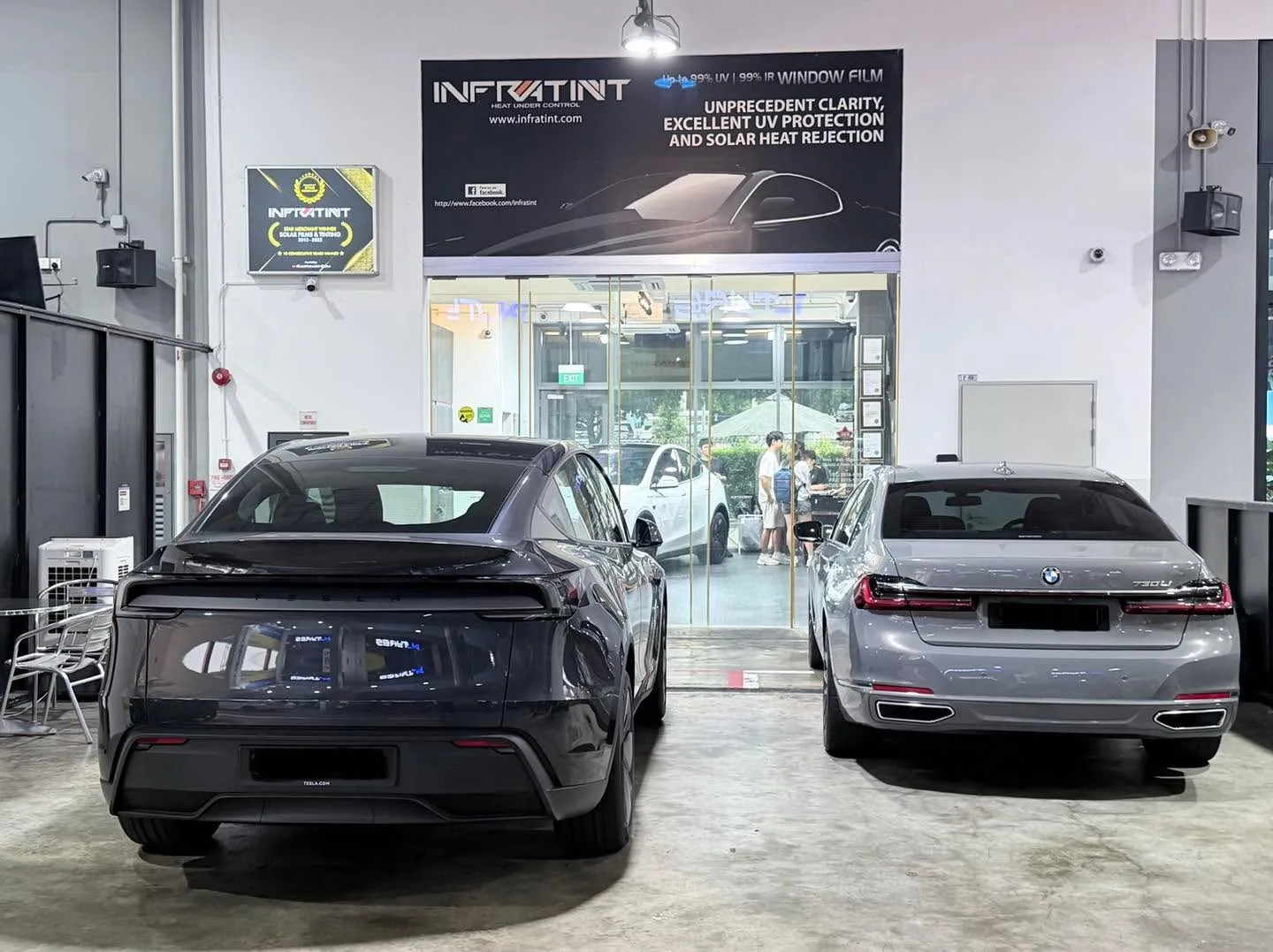 A black XPENG G6 sedan and a silver BMW sedan parked in the workshop bay.