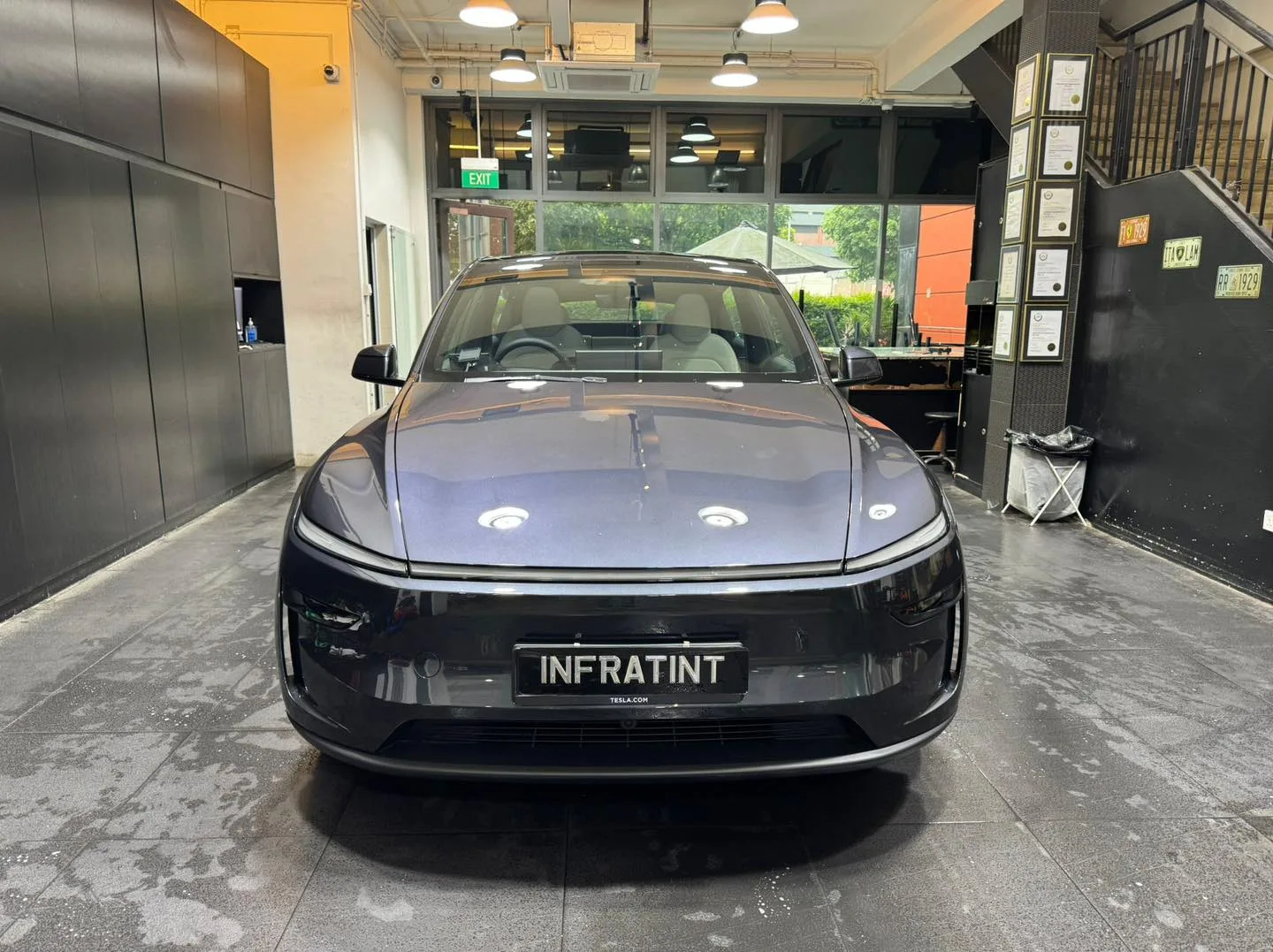A black Tesla sedan viewed from the front in the workshop.