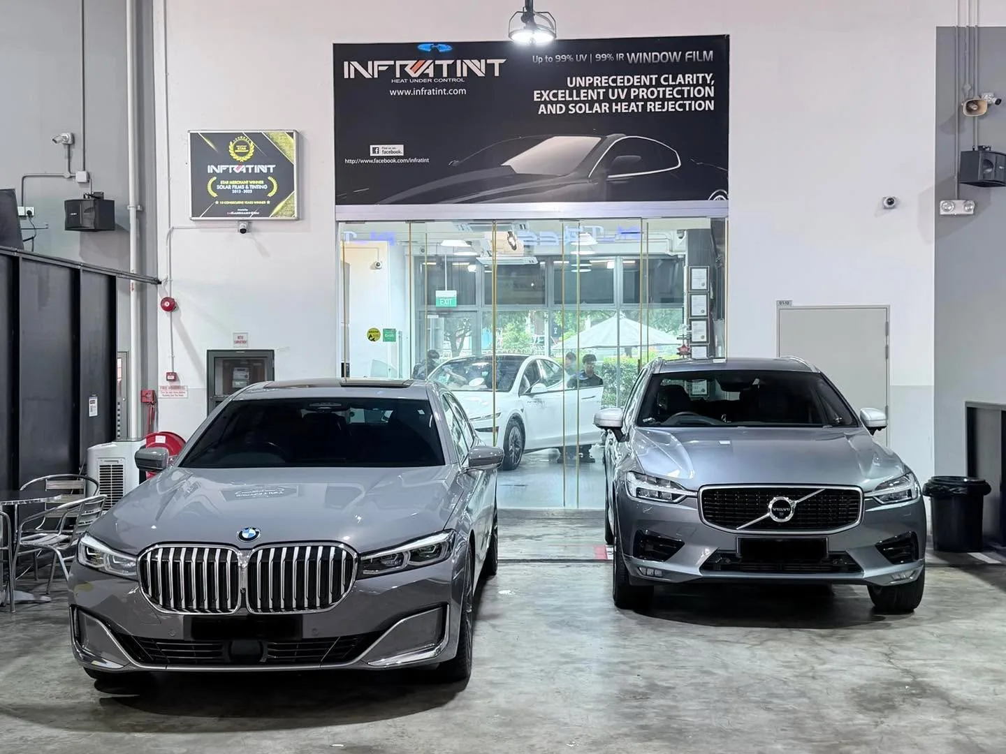 A grey BMW X4 and a silver Volvo XC60 parked inside the workshop.