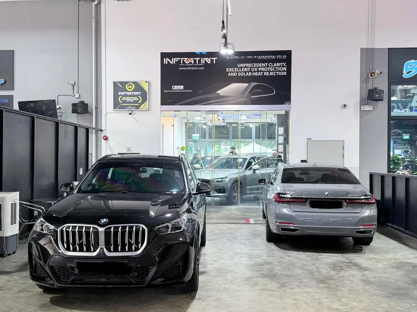 A black BMW X4 and a silver BMW X1 parked inside the workshop.