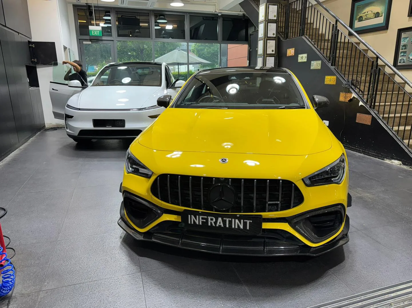 A bright yellow car with distinctive kidney grille viewed from the front inside the workshop.