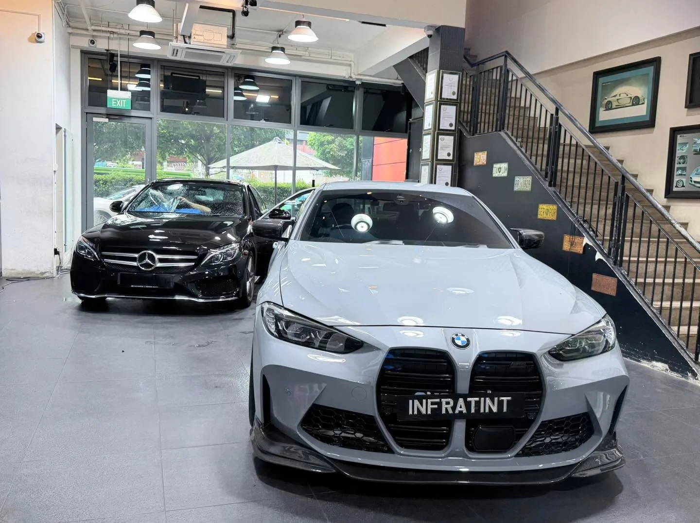 A white BMW sedan and a black Mercedes-Benz sedan parked indoors.