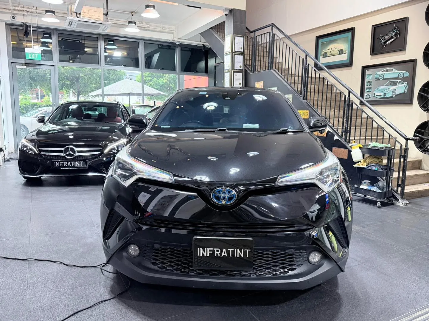 A black Mercedes-Benz sedan and a black Toyota crossover parked indoors.