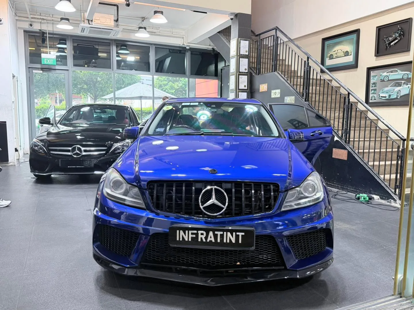 A blue Mercedes-Benz sedan and a black Mercedes-Benz sedan parked indoors.